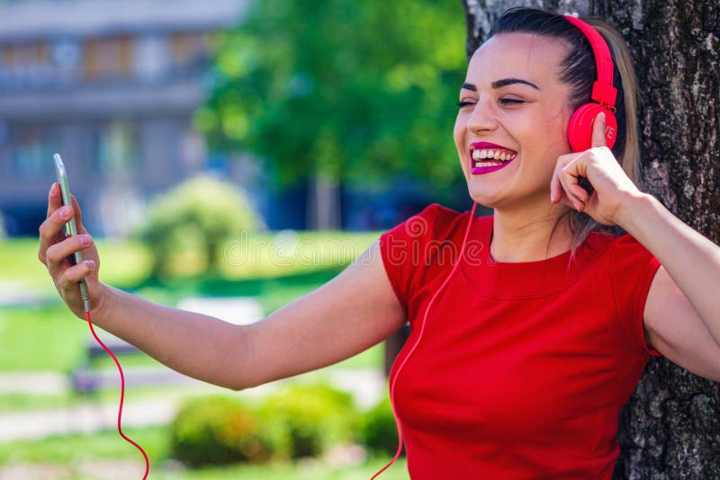 Giovane donna sorridente che fa video chiamata via lo smartphone e il headpho fotografia stock libera da diritti Giovane donna sorridente che fa video chiamata via lo smartphone e il headpho fotografia stock libera da diritti