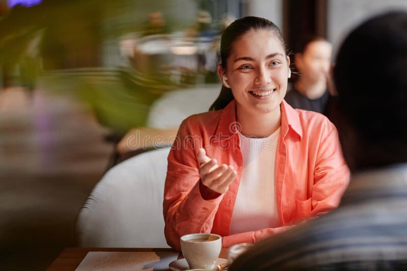 Giovane donna sorridente con cuffie che parla con un afro americano fotografie stock
