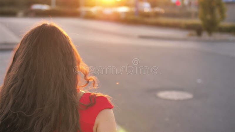 Giovane donna sorridente del sole con lo sguardo alla macchina fotografica, sorriso dei capelli ricci camminante nel ritratto fel