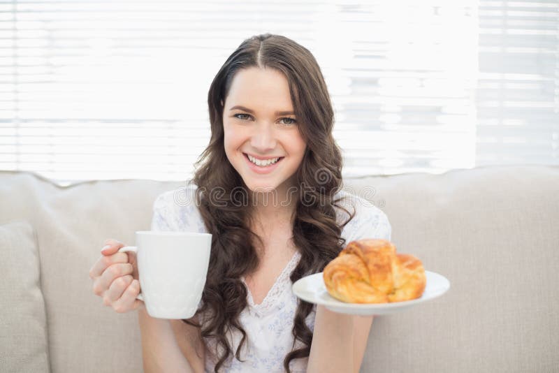 Giovane donna sorridente in pigiami che mangiano prima colazione fotografie stock libere da diritti Giovane donna sorridente in pigiami che mangiano prima colazione fotografie stock libere da diritti
