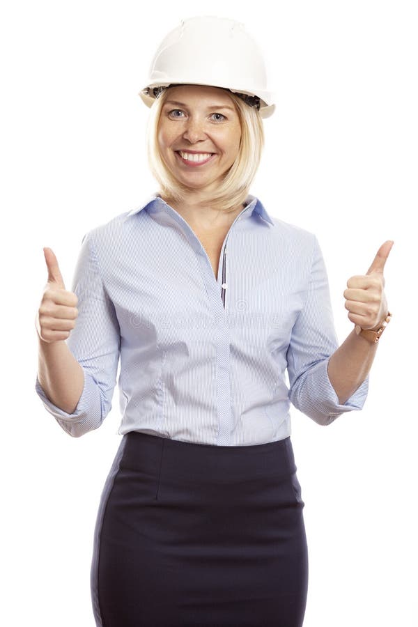 Giovane donna sorridente in vestiti dell'ufficio e un casco della costruzione sulla sua testa Pollici in su Priorit? bassa bianca fotografia stock libera da diritti Giovane donna sorridente in vestiti dell'ufficio e un casco della costruzione sulla sua testa Pollici in su Priorit? bassa bianca fotografia stock libera da diritti
