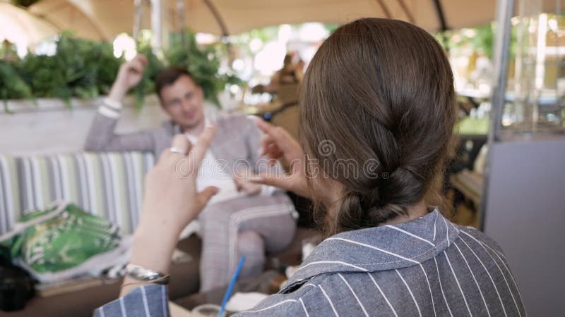 Giovane donna spiega gesti a un uomo in un ristorante a tavola