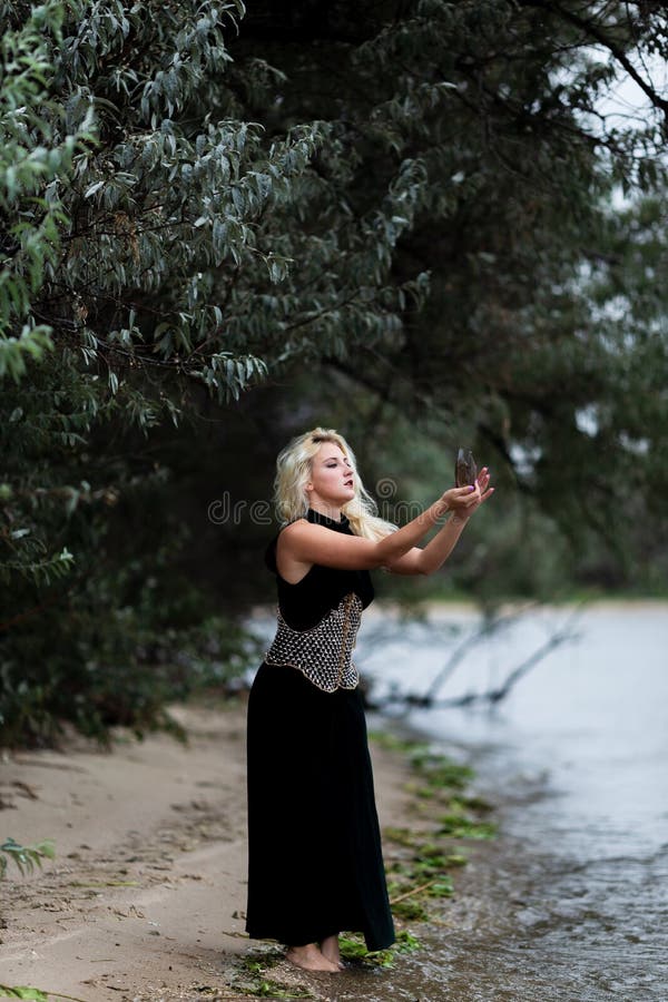 Giovane donna splendida in vestito nero lungo sulla spiaggia immagini stock libere da diritti Giovane donna splendida in vestito nero lungo sulla spiaggia immagini stock libere da diritti
