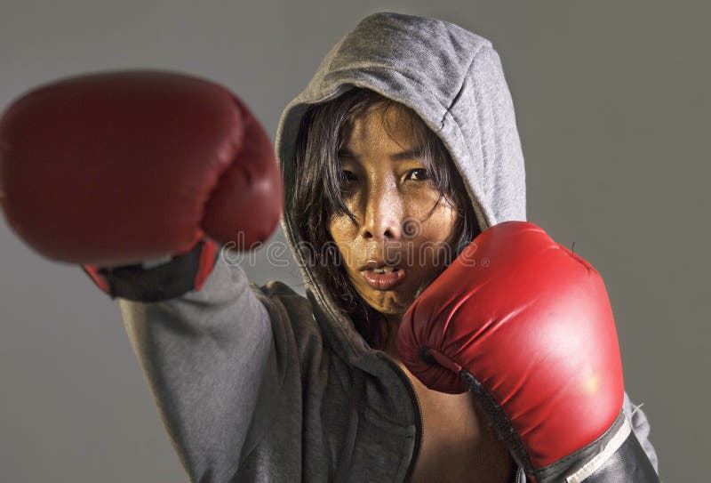 Giovane donna sportiva cinese asiatica furiosa ed arrabbiata in maglia con cappuccio della cima di forma fisica e guantoni da pug fotografia stock libera da diritti Giovane donna sportiva cinese asiatica furiosa ed arrabbiata in maglia con cappuccio della cima di forma fisica e guantoni da pug fotografia stock libera da diritti