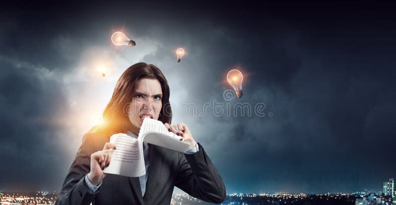 Giovane donna stressata che strappa documenti con espressione del viso frustrata. fotografie stock