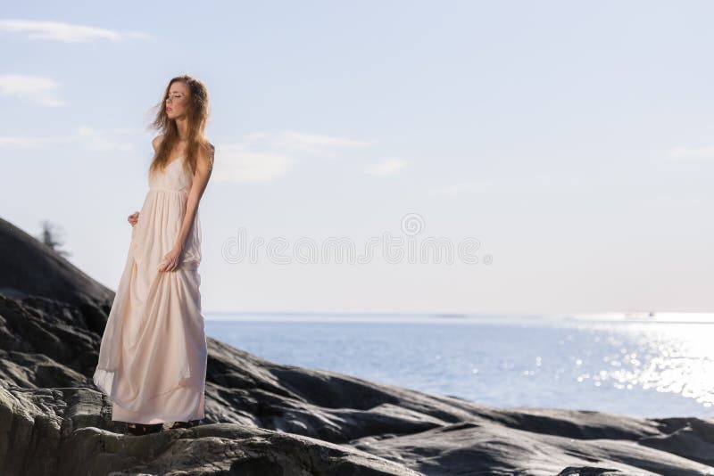 Giovane donna sulla riva rocciosa fotografia stock Giovane donna sulla riva rocciosa fotografia stock