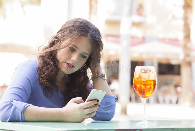 Giovane donna sulla sua rottura che legge un messaggio di testo sul cellulare fotografia stock Giovane donna sulla sua rottura che legge un messaggio di testo sul cellulare fotografia stock