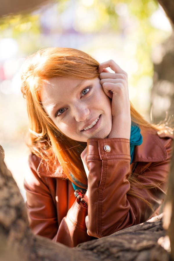 Giovane donna sveglia allegra positiva che posa vicino all'albero in parco fotografia stock libera da diritti Giovane donna sveglia allegra positiva che posa vicino all'albero in parco fotografia stock libera da diritti