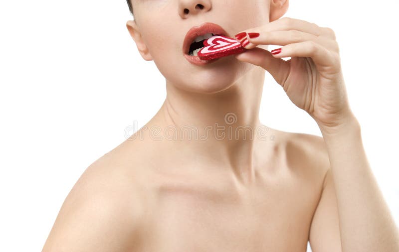Giovane donna Topless che mangia la caramella a forma di del cuore immagini stock Giovane donna Topless che mangia la caramella a forma di del cuore immagini stock