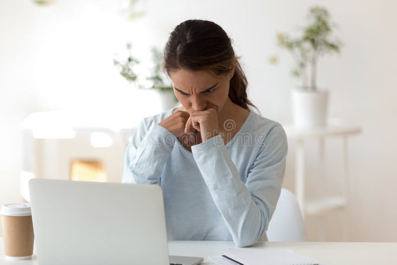 Giovane donna triste che si siede allo scrittorio che esamina schermo di computer immagini stock libere da diritti Giovane donna triste che si siede allo scrittorio che esamina schermo di computer immagini stock libere da diritti