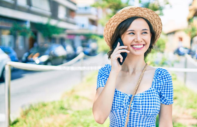 Giovane e bella ragazza che sorride felice usando lo smartphone che cammina per la strada della città fotografia stock libera da diritti