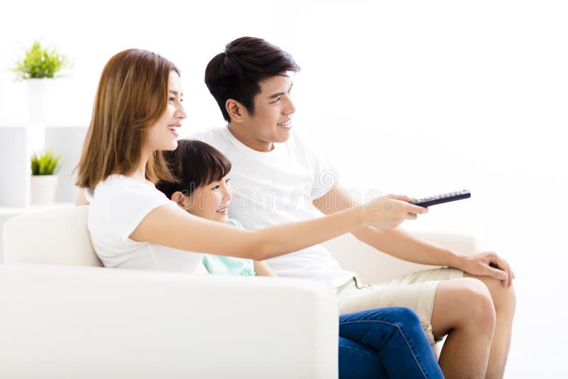Giovane famiglia attraente felice che guarda la TV fotografia stock libera da diritti Giovane famiglia attraente felice che guarda la TV fotografia stock libera da diritti