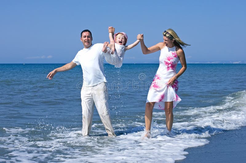 Giovane famiglia che gioca con la figlia sulla spiaggia in Spagna immagine stock