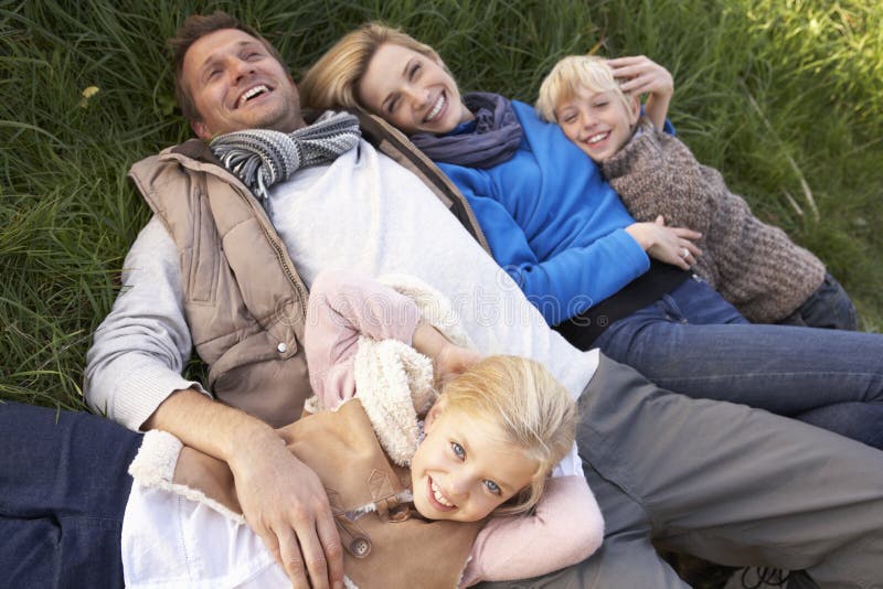 Giovane famiglia che si trova insieme sull'erba fotografia stock Giovane famiglia che si trova insieme sull'erba fotografia stock