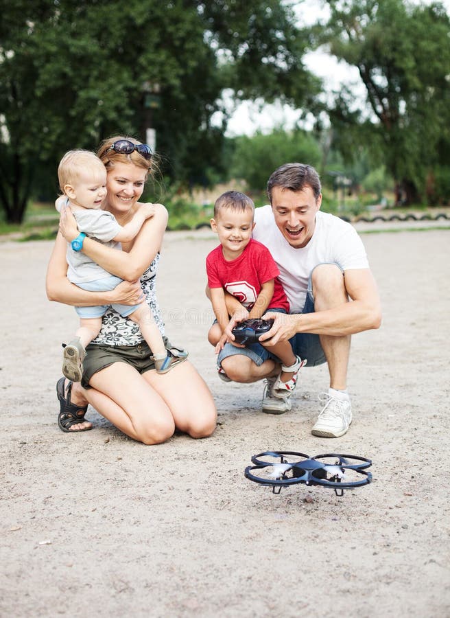 Giovane famiglia con due ragazzi che giocano con il giocattolo di RC fotografia stock libera da diritti Giovane famiglia con due ragazzi che giocano con il giocattolo di RC fotografia stock libera da diritti