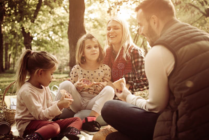 Giovane famiglia felice che gode insieme nel picnic nella foresta fotografie stock Giovane famiglia felice che gode insieme nel picnic nella foresta fotografie stock