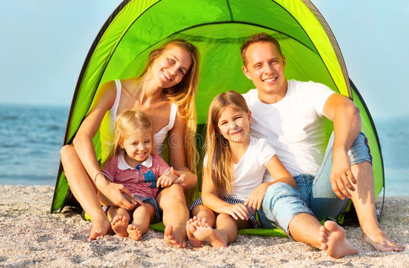 Happy young family camping on the beach. Summertime. Happy young family camping on the beach. Summertime