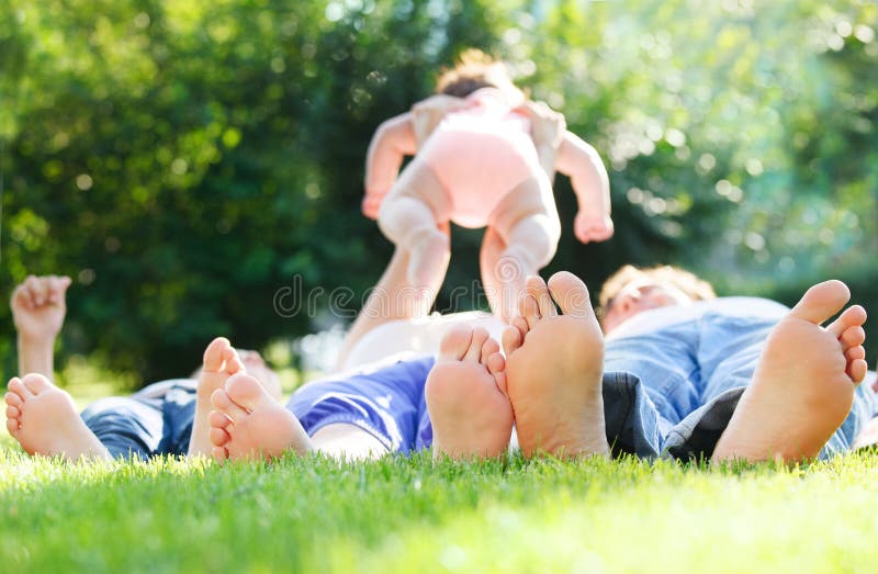 Giovane famiglia felice che si trova sull'erba verde all'aperto immagine stock Giovane famiglia felice che si trova sull'erba verde all'aperto immagine stock