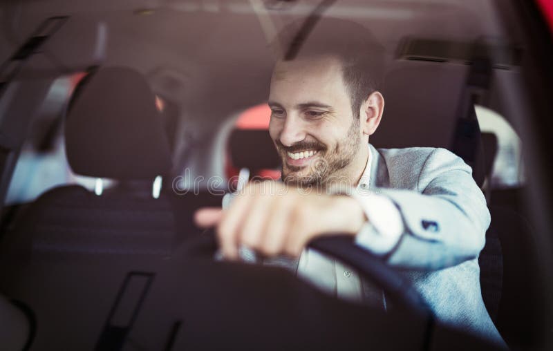 Giovane felice attraente che determina automobile e sorridere fotografie stock libere da diritti Giovane felice attraente che determina automobile e sorridere fotografie stock libere da diritti