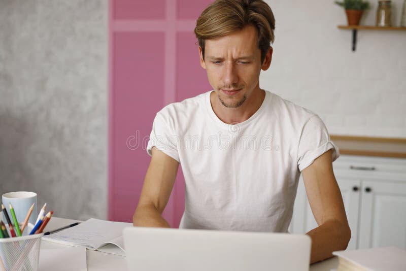 Giovane freelancer usa il laptop che studia online lavorando da un ragazzo allegro e felice che batte a macchina su un quaderno pc fotografia stock libera da diritti