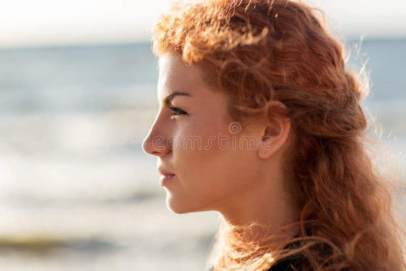 Giovane fronte felice della donna della testarossa sulla spiaggia fotografia stock libera da diritti Giovane fronte felice della donna della testarossa sulla spiaggia fotografia stock libera da diritti