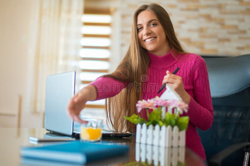 Giovane funzionamento castana alla sua scrivania con i documenti ed il computer portatile Donna di affari che lavora al lavoro di fotografie stock Giovane funzionamento castana alla sua scrivania con i documenti ed il computer portatile Donna di affari che lavora al lavoro di fotografie stock
