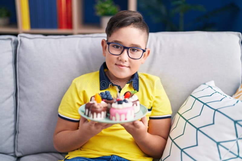 Giovane ispanico che regge dolci di torta sorridendo con un sorriso felice e fresco sulla faccia fotografia stock