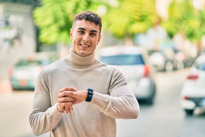 Giovane ispanico sorridente felice con l'orologio della città immagine stock libera da diritti