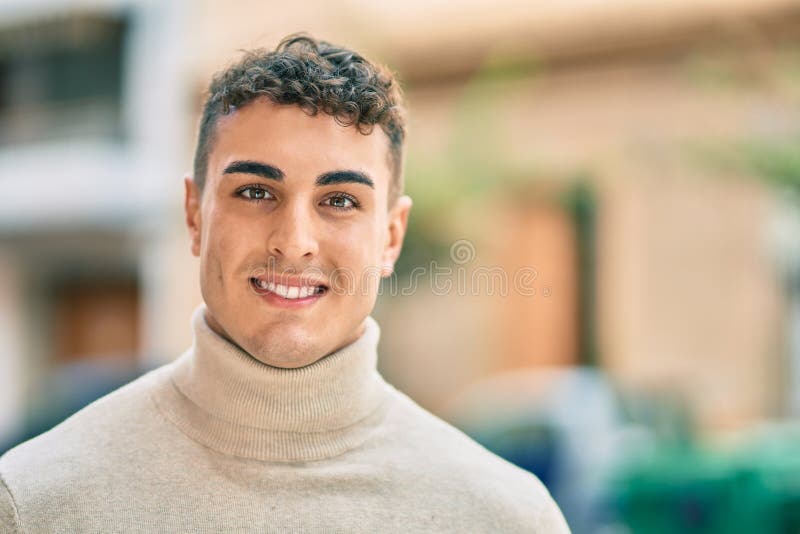 Giovane ispanico sorridente felice di essere in città fotografia stock