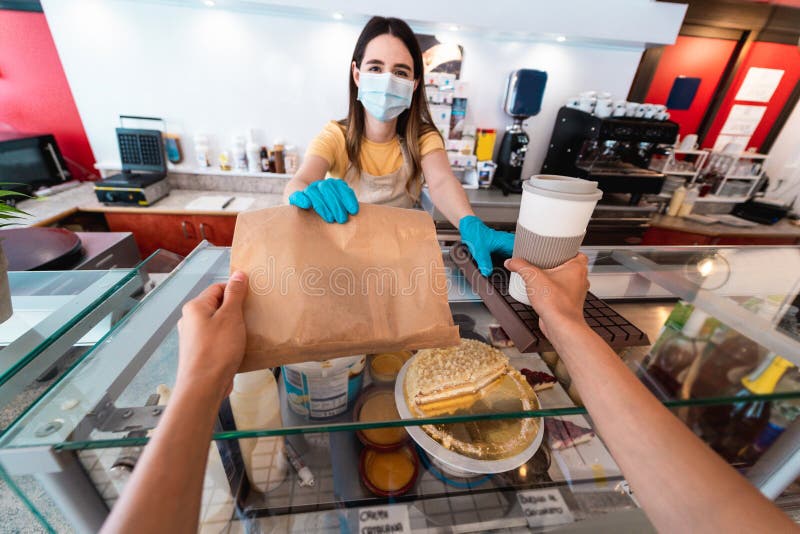 Giovane lavoratrice che fa colazione al bar alla mensa con una maschera di sicurezza durante l'epidemia di coronavirus