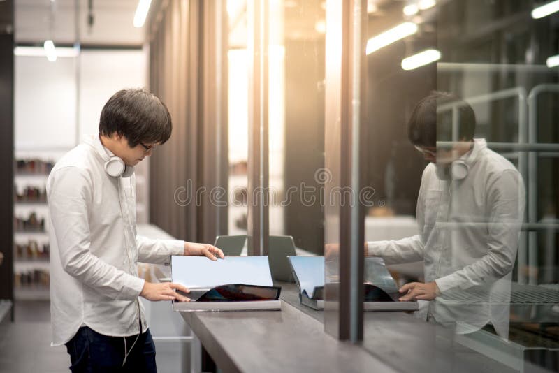 Giovane libro asiatico di apertura dello studente universitario dell'uomo in biblioteca immagini stock libere da diritti Giovane libro asiatico di apertura dello studente universitario dell'uomo in biblioteca immagini stock libere da diritti