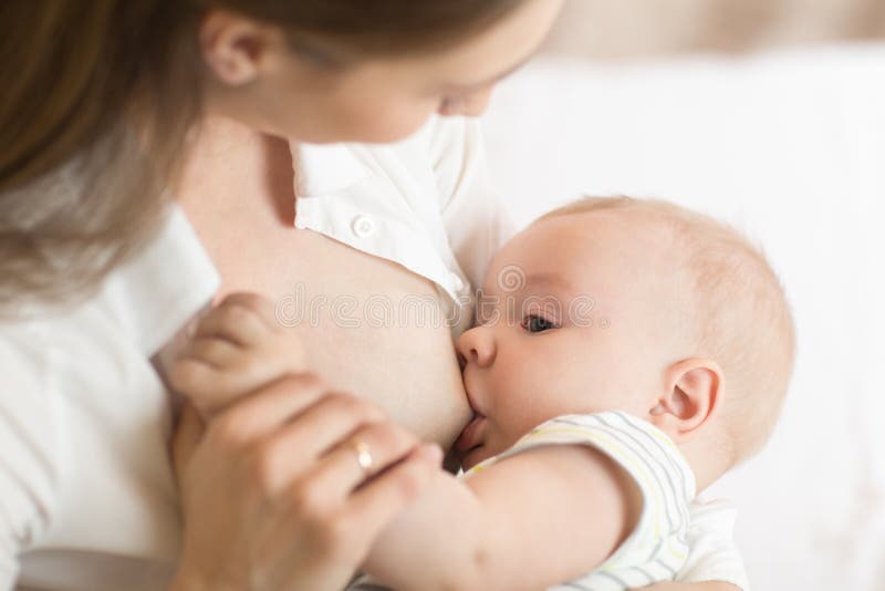 Giovane madre che tiene il suo bambino neonato Bambino di professione d'infermiera della mamma Bambino grazioso di allattamento a immagine stock libera da diritti Giovane madre che tiene il suo bambino neonato Bambino di professione d'infermiera della mamma Bambino grazioso di allattamento a immagine stock libera da diritti