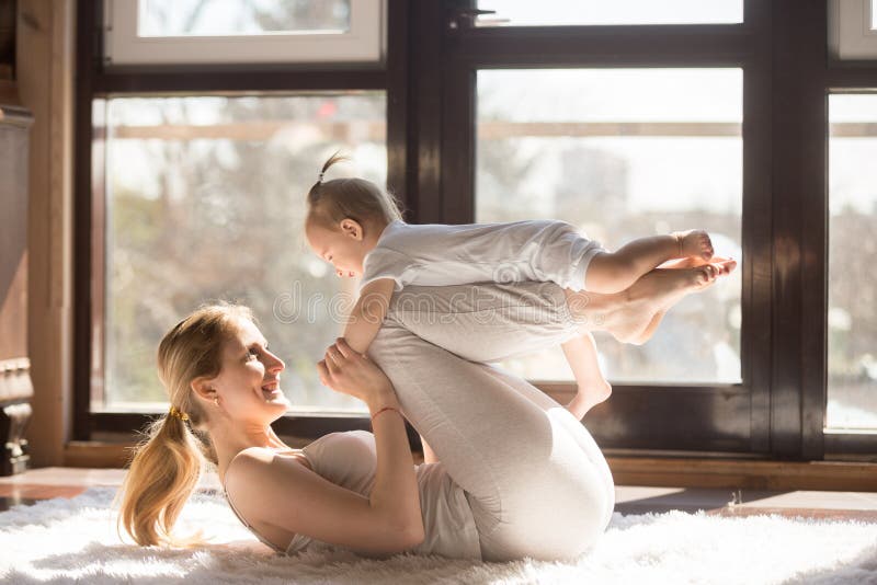 Giovane madre sorridente degli Yogi e sua la figlia del bambino che esercitano toget immagini stock Giovane madre sorridente degli Yogi e sua la figlia del bambino che esercitano toget immagini stock