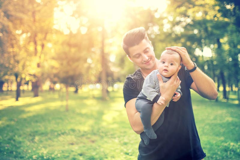 Giovane maschio, padre che tiene 3 mesi dell'infante e che si diverte in parco Concetto del figlio e del padre in natura fotografia stock libera da diritti Giovane maschio, padre che tiene 3 mesi dell'infante e che si diverte in parco Concetto del figlio e del padre in natura fotografia stock libera da diritti