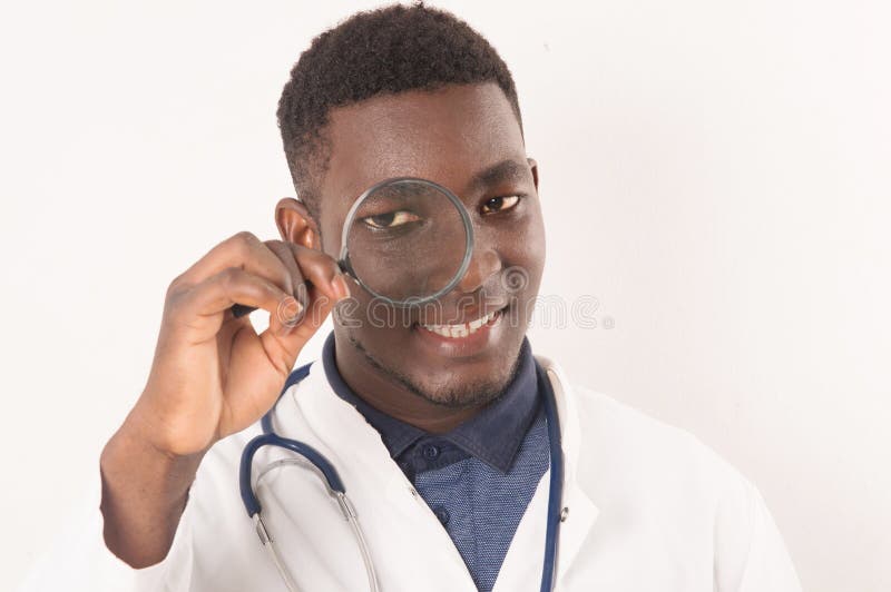 Giovane medico che guarda in una lente d'ingrandimento immagine stock libera da diritti Giovane medico che guarda in una lente d'ingrandimento immagine stock libera da diritti