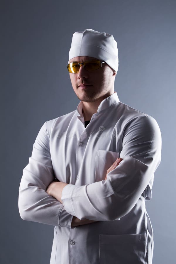 Giovane medico maschio in cappuccio e vetri gialli alla luce di contrapposizione immagine stock Giovane medico maschio in cappuccio e vetri gialli alla luce di contrapposizione immagine stock