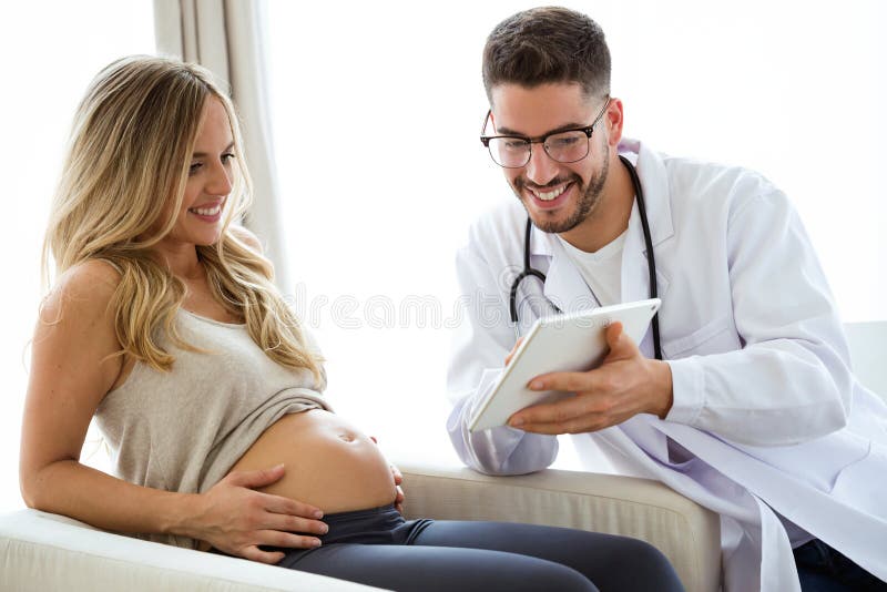 Giovane medico maschio del ginecologo che mostra al bambino di ricerca di ultrasuono della donna incinta con la compressa digital fotografia stock libera da diritti Giovane medico maschio del ginecologo che mostra al bambino di ricerca di ultrasuono della donna incinta con la compressa digital fotografia stock libera da diritti