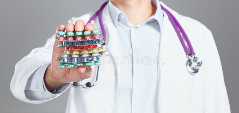 Giovane medico tiene la mano paziente del ` s con le pillole fotografia stock Giovane medico tiene la mano paziente del ` s con le pillole fotografia stock