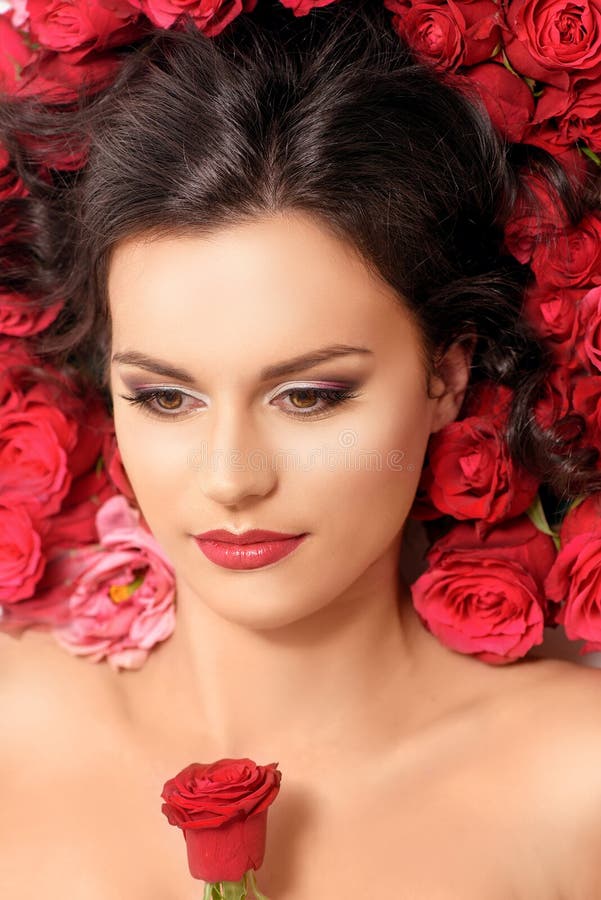 Giovane menzogne di modello nelle rose rosse fotografie stock