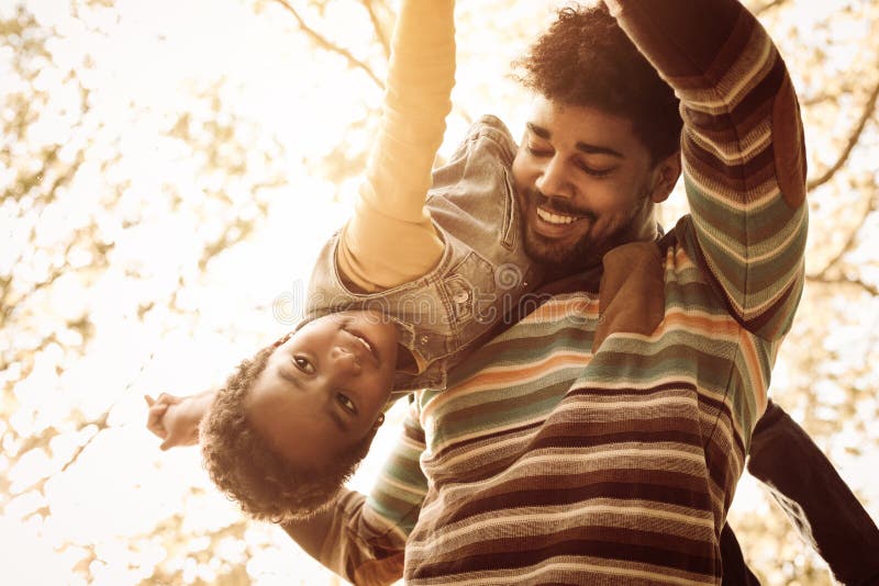 Giovane padre afroamericano in parco che porta sua figlia sulla s fotografia stock Giovane padre afroamericano in parco che porta sua figlia sulla s fotografia stock