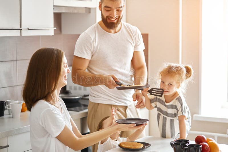 Giovane padre allegro che lancia pancake in cucina immagini stock libere da diritti Giovane padre allegro che lancia pancake in cucina immagini stock libere da diritti