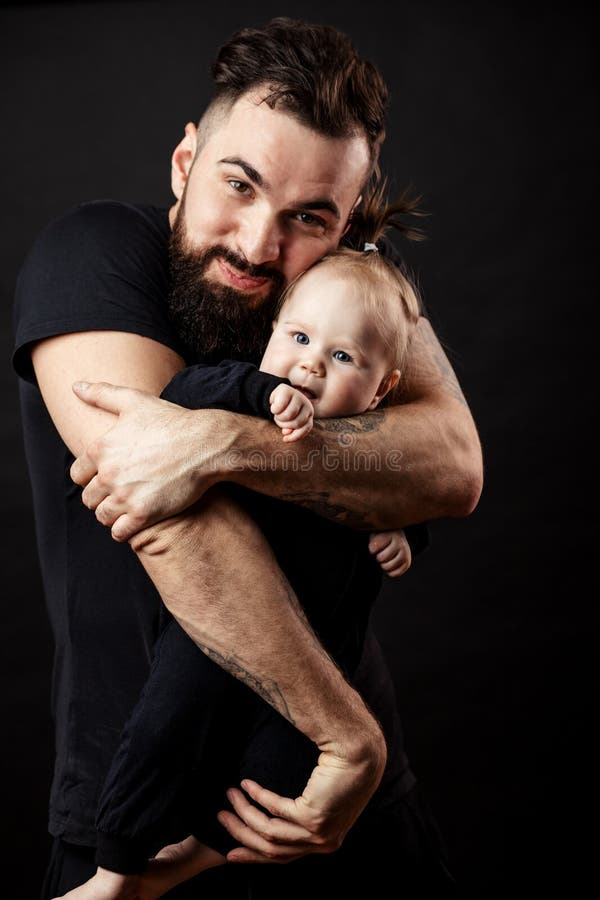 Giovane padre atletico con il bambino adorabile su fondo nero fotografie stock Giovane padre atletico con il bambino adorabile su fondo nero fotografie stock