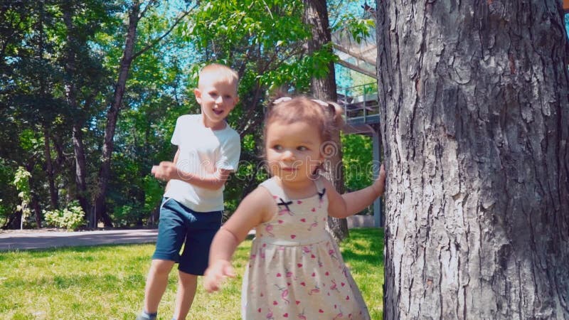 Giovane padre con i bambini che vanno in giro un albero vicino alla casa, alla figlia del papà, del figlio e del bambino diverten