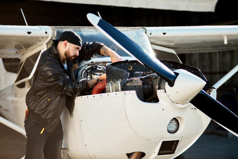 Giovane pilota con gli strumenti che controlla sul motore del getto d'aria leggero dell'elica immagine stock libera da diritti Giovane pilota con gli strumenti che controlla sul motore del getto d'aria leggero dell'elica immagine stock libera da diritti
