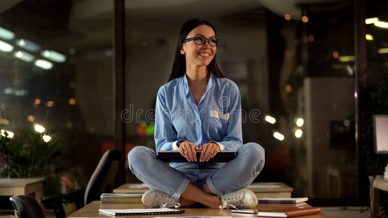 Giovane posa di seduta di tenuta femminile del loto del computer portatile, soddisfatta di lavoro fatto, successo fotografia stock libera da diritti Giovane posa di seduta di tenuta femminile del loto del computer portatile, soddisfatta di lavoro fatto, successo fotografia stock libera da diritti
