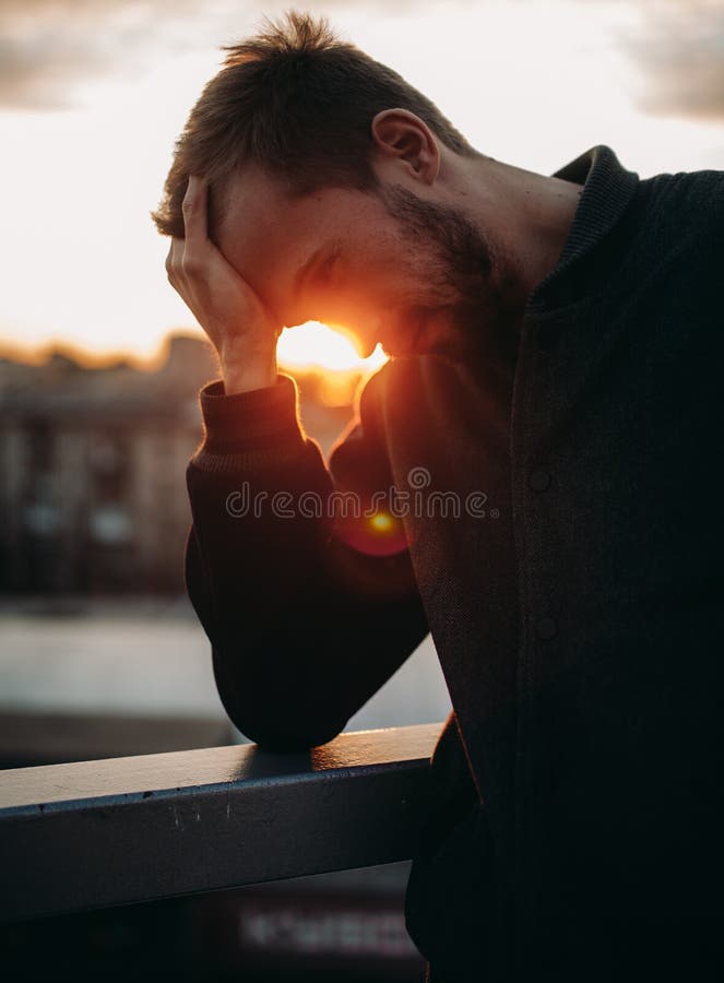 Giovane premuroso su fondo di paesaggio urbano al tramonto fotografia stock libera da diritti Giovane premuroso su fondo di paesaggio urbano al tramonto fotografia stock libera da diritti