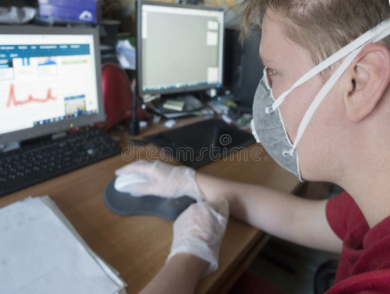 Giovane programmatore maschile che lavora al computer con una maschera protettiva e guanti immagine stock