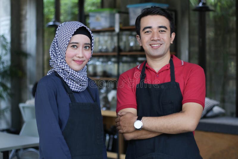 Giovane proprietario asiatico felice del caffè delle coppie davanti a sorridere della caffetteria un ritratto di due camerieri al fotografie stock Giovane proprietario asiatico felice del caffè delle coppie davanti a sorridere della caffetteria un ritratto di due camerieri al fotografie stock