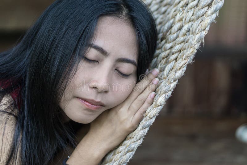 Giovane ragazza asiatica caucasica che oscilla in un'amaca in una pigrizia piacevole di una sera di fine settimana fotografia stock libera da diritti Giovane ragazza asiatica caucasica che oscilla in un'amaca in una pigrizia piacevole di una sera di fine settimana fotografia stock libera da diritti