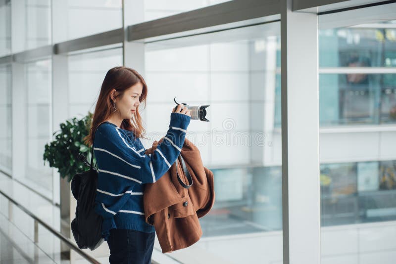 Giovane ragazza asiatica del viaggiatore con lo zaino che prende una foto con la sua macchina fotografica digitale immagine stock libera da diritti Giovane ragazza asiatica del viaggiatore con lo zaino che prende una foto con la sua macchina fotografica digitale immagine stock libera da diritti